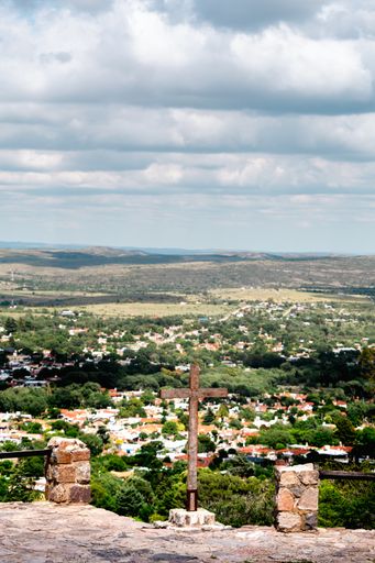 A vertical shot of a big metal cross on the top of the hill