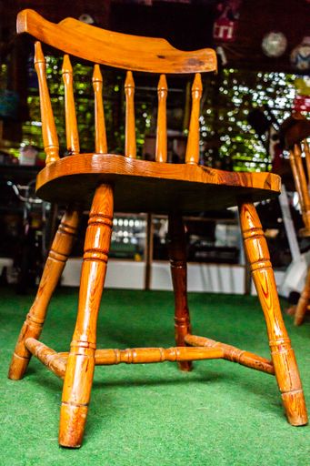 A vertical shot of a simple wooden chair in a cafe under the lights with a blurry backgrou