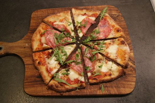 A closeup shot of a Sweden homemade pizza with arugula and ham.