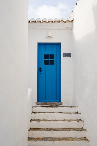 A vertical shot of a blue door in a Portuguese small romantic village.
