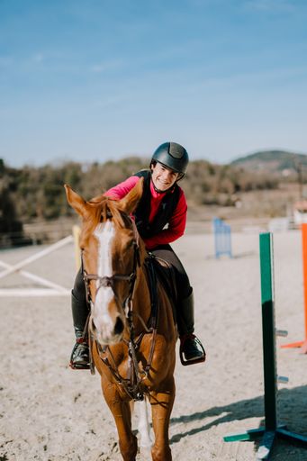 A vertical shot of a girl during horseback riding on a sunny day