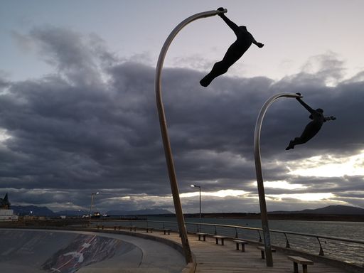 A closeup shot of statues of athletes on the deck near the sea under a cloudy sky