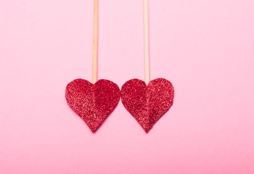 A closeup shot of two arrows made from red, sparkling  heart-shaped sequins