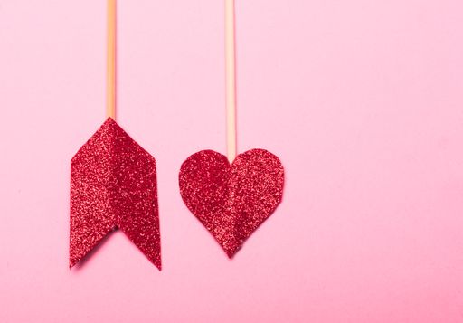 A closeup shot of two arrows made from red, sparkling  heart-shaped sequins