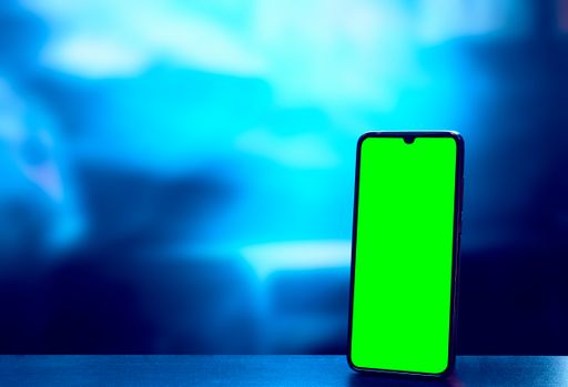 A closeup shot of a green screen on a mobile phone against a blue blurry background