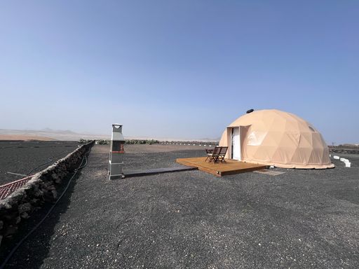 A modern dome house near the beach on blue sky background