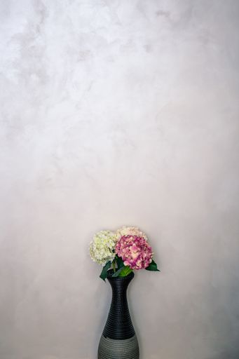 A vertical shot of a beautiful bouquet with colorful flowers in a vase on a white wall background
