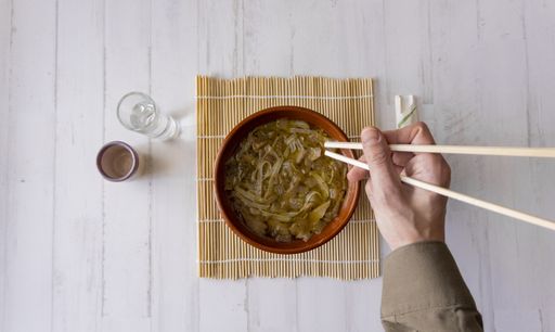 An overhead shot of a Japanese shoop with chopsticks on a white wooden background