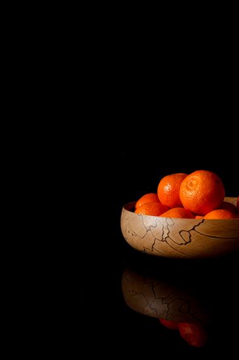 A vase of ripe mandarins in the black background with a copy space