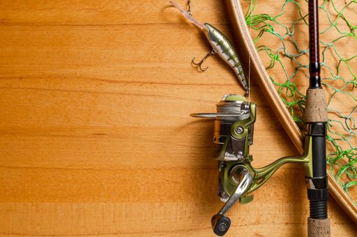 Fishing tackle, fishing spinning rod on wooden background. Active hobby recreation concept. Top view, flat lay. selective focus on spool