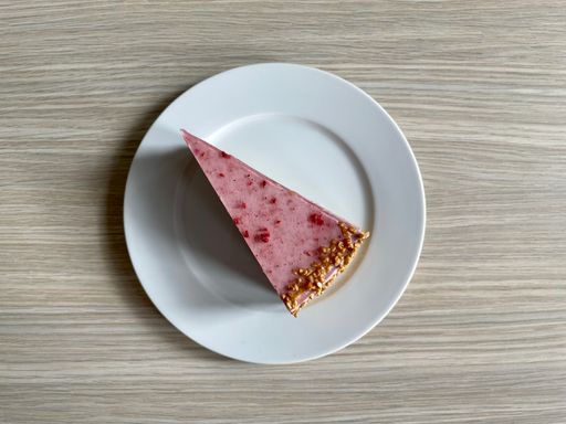 A top view of a piece of strawberry cake with caramel crumb on the side and topped with strawberry powder.