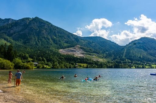 People bathing at a lake beach close by the Alp mountains.