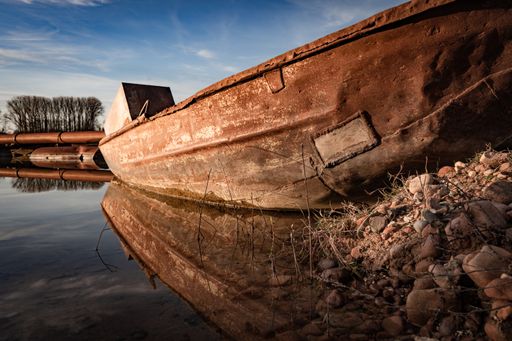 A closeup of an old rusty abandoned ship on the shore under the sunlight and a blue sky