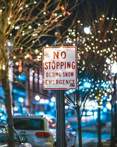 A closeup of a street sign text NO STOPPING DURING SNOW EMERGENCY in downtown Columbus, USA at night