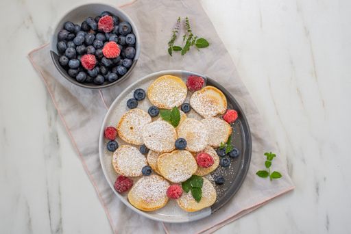 A top view of homemade fluffy pancake with raspberries and blueberries
