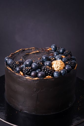 A vertical shot of a chocolate cake with blueberries and blackberries