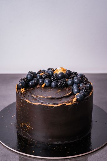 A vertical shot of a chocolate cake with blueberries and blackberries