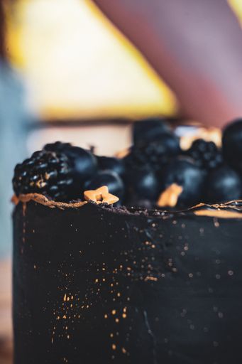 A vertical shot of a chocolate cake with blueberries and blackberries