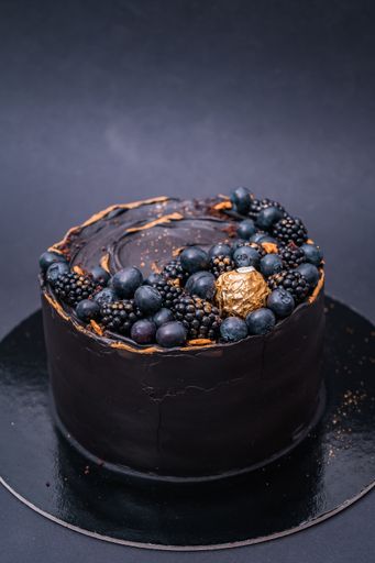 A vertical shot of a chocolate cake with blueberries and blackberries