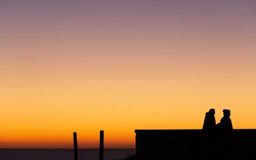 A silhouette view of a couple standing against dusk sky at sunset