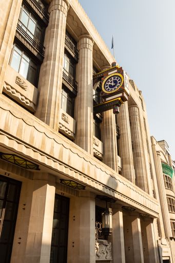 A closeup of a building in London with a clock hanging on the wall