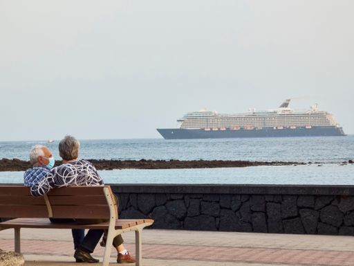 A closeup of an elderly couple seen from behind sitting on a bench overlooking the sea