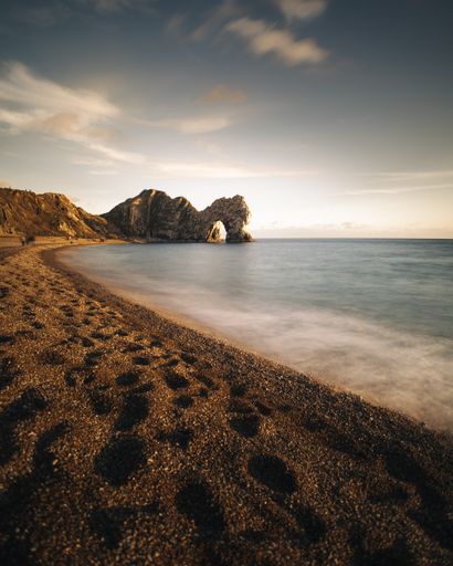 A tranquil coastal scene featuring the iconic Durdle Door rock formation in Lulworth Cove, Dorset