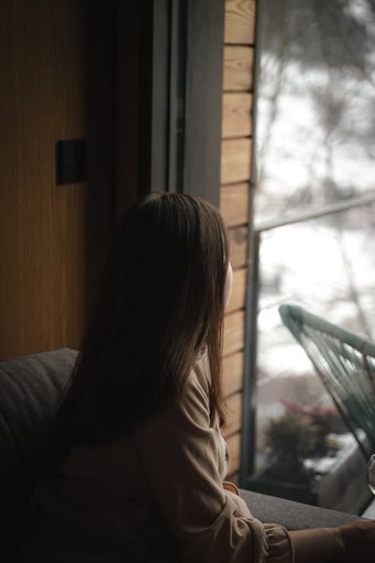 A vertical shot of a Caucasian woman standing near the window