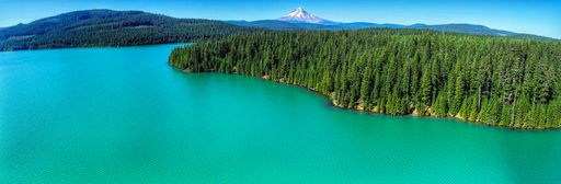 A panoramic view of a lake surrounded by green mountains on a sunny day