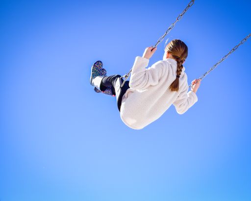 A closeup of a girl on a swing with blue sky backgroun