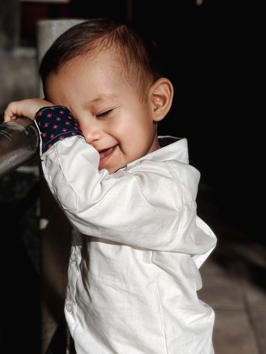 A selective focus shot of a laughing cute baby boy in a white shirt