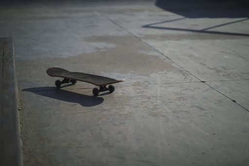 A shallow focus shot of a black skateboard on a concrete floor at the park during daytime