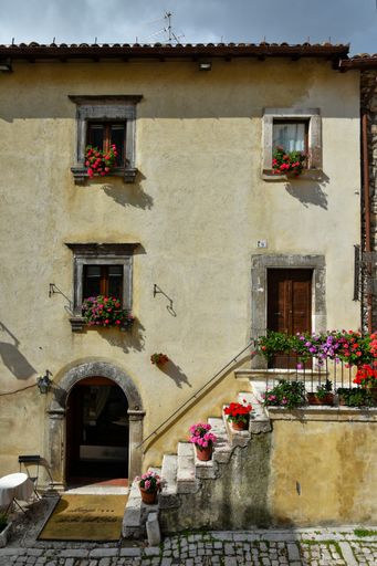 The facade of an old house adorned with flowers in Pecocostanzo
