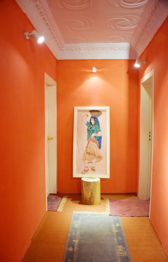A vertical shot of a painting by symbolist painter Gustav Klimt in the orange corridor of the museum