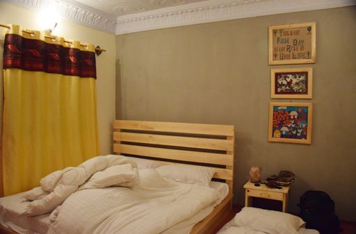 A view of a cozy bedroom with wooden bed and pictures