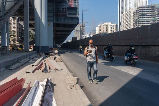 A shot of a man walking on the road and scrolling the phone in Malad, Mumbai, India