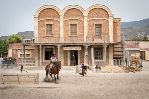 A Wild west movie set with men fighting and a galloping horse