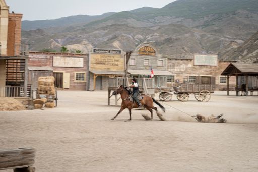 A Wild west movie set with men fighting and a galloping horse