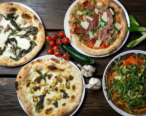 A top view of various pizzas on a wooden surface