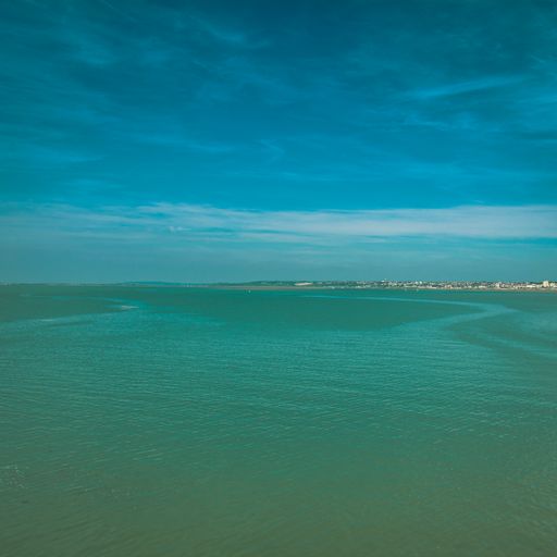 A scenic view of a blue ocean on cloudy sky background