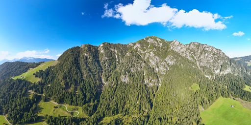 Aerial panorama of an alpine landscape with blue sky. Spectacular mountain ridge with small valleys. Hiking vacation in Tyrol, Austria.
