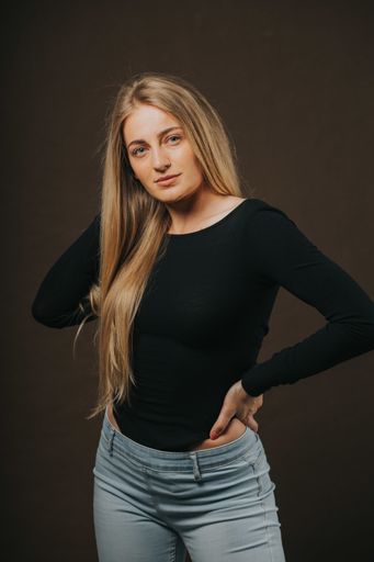 A vertical shot of an attractive blonde female posing while sitting on a barstool