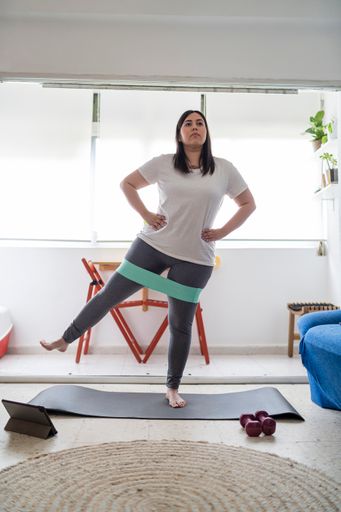 A vertical shot of the Caucasian female doing a workout with resistance band