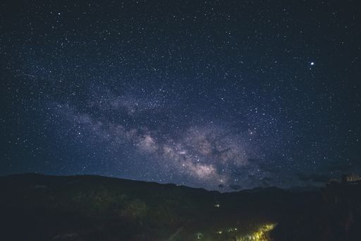A wide shot of the beautiful starry sky above hills and mountains in the countryside