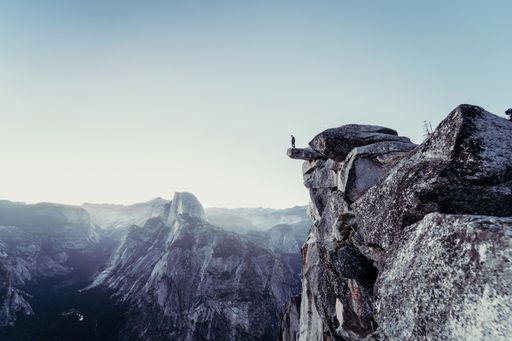 A beautiful shot of rocky mountains with a person standing on the edge