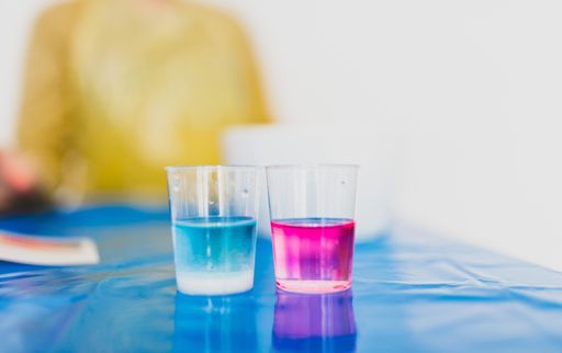 A closeup shot of pink and blue drinks in the glasses on a blue surface