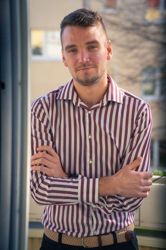 A selective focus shot of a young smiling male on the balcony