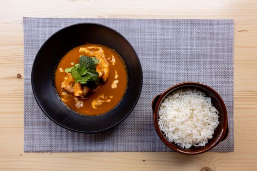 A top view of a meal with shrimps in the yellow souse with rice on the side