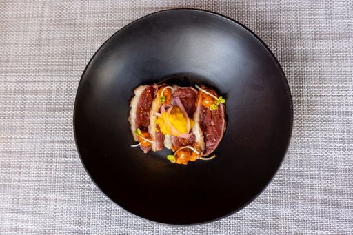 A top view of a meal with fresh roast beef and yellow sous