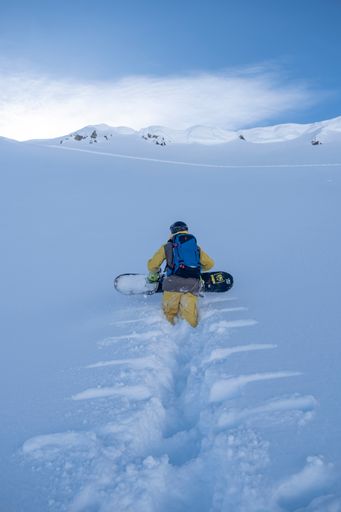A vertical shot of a person getting ready to snowboard in the hills in Andermatt, Switzerland